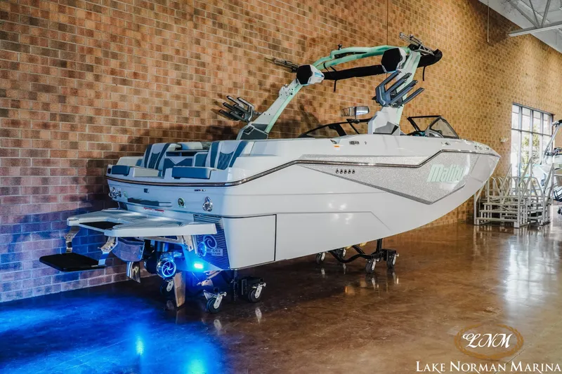Slide: The Image of 2026 Malibu M230 boat displayed indoors with blue lighting at Lake Norman Marina. - 3