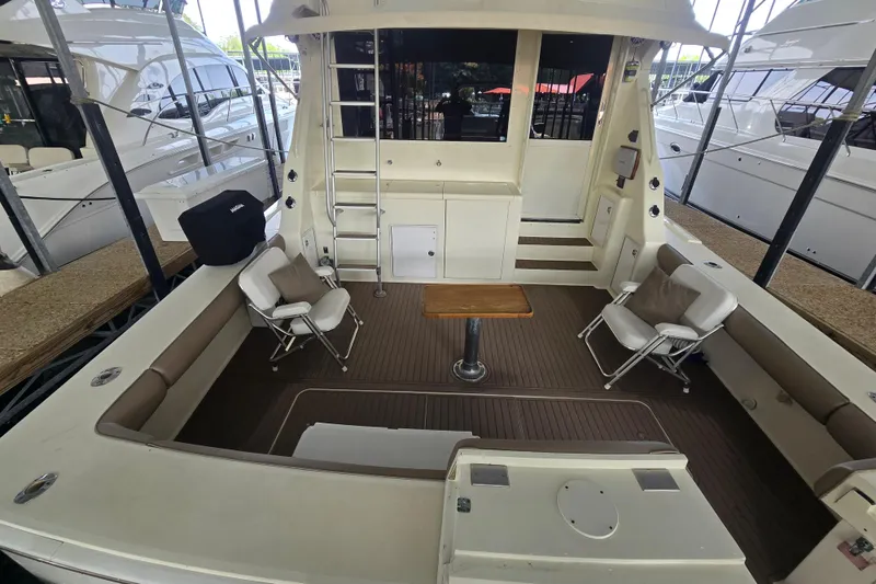 Slide: The Image of 1990 Viking 53 Convertible yacht interior with seating, table, and ladder in a marina setting. - 22