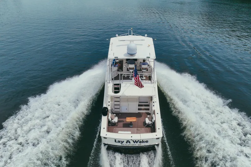 Slide: The Image of 1990 Viking 53 Convertible yacht cruising on open water, rear view with American flag. - 4