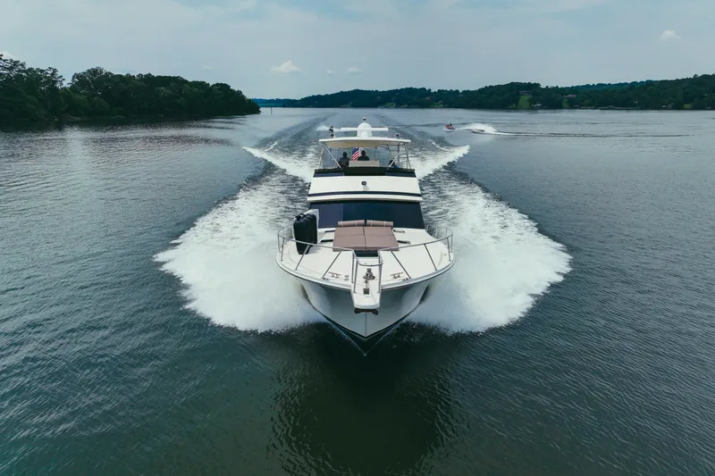 Slide: The Image of 1990 Viking 53 Convertible yacht cruising on a serene lake, leaving a wake behind. - 6