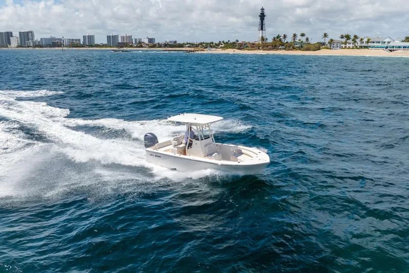 Slide: The Image of 2025 Sea Born LX22 Center Console boat cruising near a coastal lighthouse. - 15