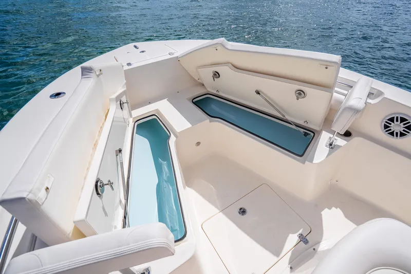 Slide: The Image of 2025 Sea Born LX22 Center Console boat interior with storage compartments open on calm water. - 29