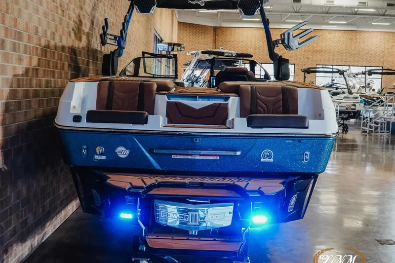 Slide: The Image of 2026 Malibu Wakesetter 25 LSV boat with blue hull and brown seating in showroom. - 7