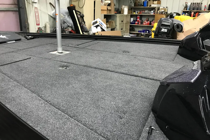 Slide: The Image of 2026 Lund 1875 Pro-V Bass XS boat interior with carpeted deck in a workshop. - 10