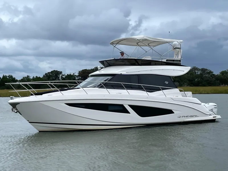 The Image of 2022 Regal 42 FXO yacht cruising on a calm waterway under cloudy skies. - 0