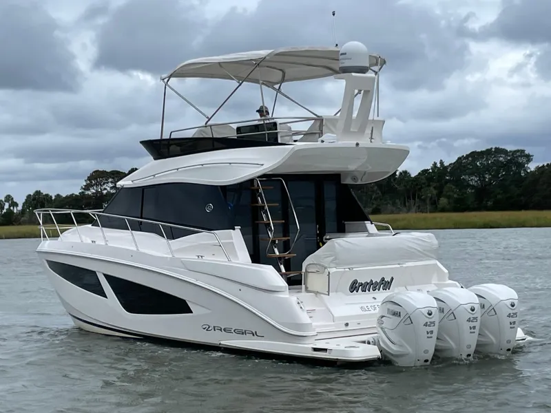 Slide: The Image of 2022 Regal 42 FXO yacht with triple outboard engines on a calm waterway. - 2