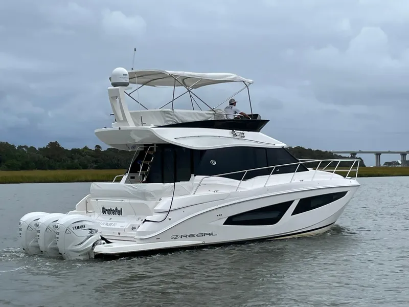 Slide: The Image of 2022 Regal 42 FXO yacht cruising on a calm river with overcast skies. - 3