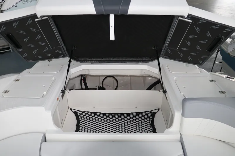 Slide: The Image of 2026 Chaparral 23 SSi OB boat storage compartment with open hatch and netting. - 21