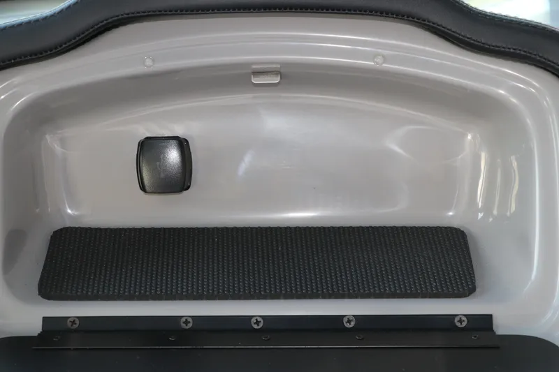 Slide: The Image of 2026 Chaparral 23 SSi OB boat interior compartment with black latch and textured mat. - 31