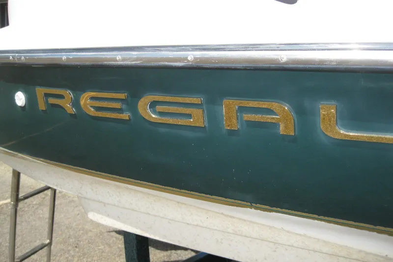 Slide: The Image of 1997 Regal 2100 LSR boat with gold lettering on a dark green hull. - 3