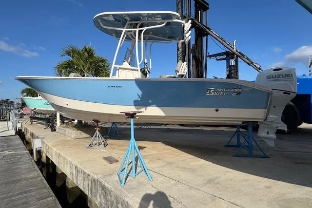 The Image of 2024 Carolina Skiff 22 Ultra Elite boat on stands, blue hull, Suzuki outboard, sunny day. - 1
