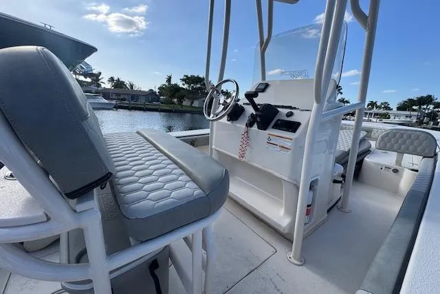 Slide: The Image of 2024 Carolina Skiff 22 Ultra Elite boat interior with seating and console, docked by a waterfront. - 10