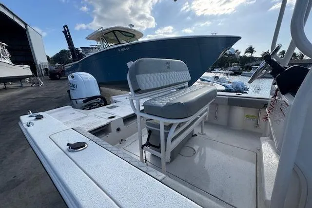 Slide: The Image of 2024 Carolina Skiff 22 Ultra Elite boat docked, featuring seating and Suzuki outboard motor. - 13