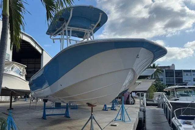 Slide: The Image of 2024 Carolina Skiff 22 Ultra Elite boat on display, blue and white hull, marina setting. - 4