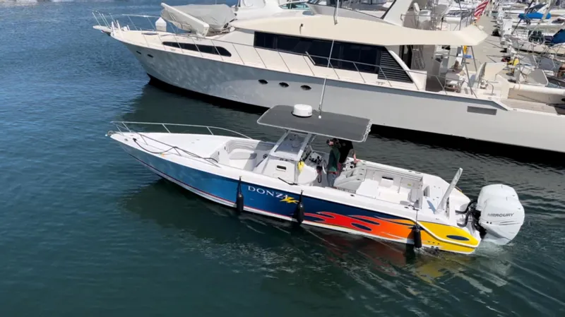 Slide: The Image of 2004 Donzi 35 ZF Cuddy boat with vibrant graphics docked in marina. - 2