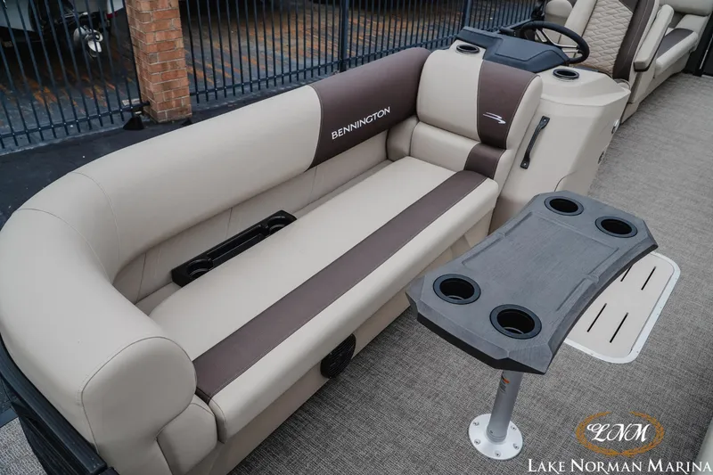 Slide: The Image of 2026 Bennington 23SSR pontoon boat interior with beige seating and cup holder table. - 15