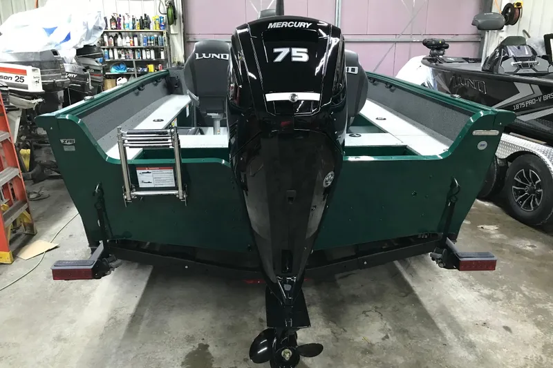 Slide: The Image of 2026 Lund 1700 Explorer Tiller boat with Mercury 75 engine in a garage setting. - 11
