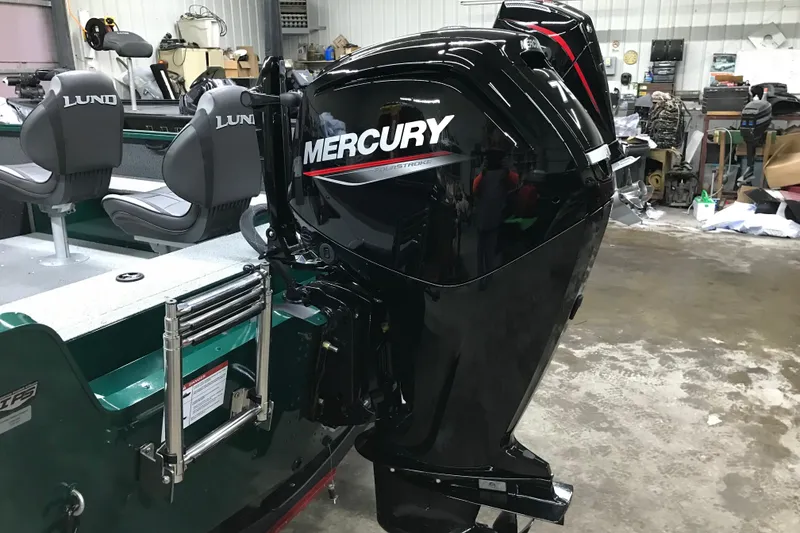 Slide: The Image of 2026 Lund 1700 Explorer Tiller with Mercury outboard motor in a garage setting. - 12