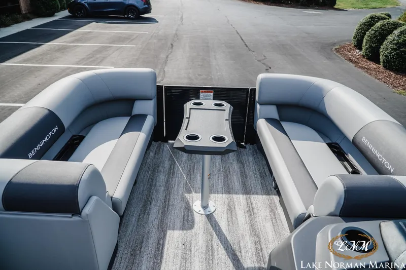 Slide: The Image of 2026 Bennington 22SSR pontoon boat interior with gray seating and table, parked at Lake Norman Marina. - 12