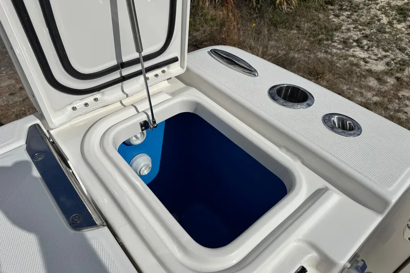 Slide: The Image of Open storage compartment on 2026 Solace 30 CS boat, featuring cup holders and blue interior. - 13