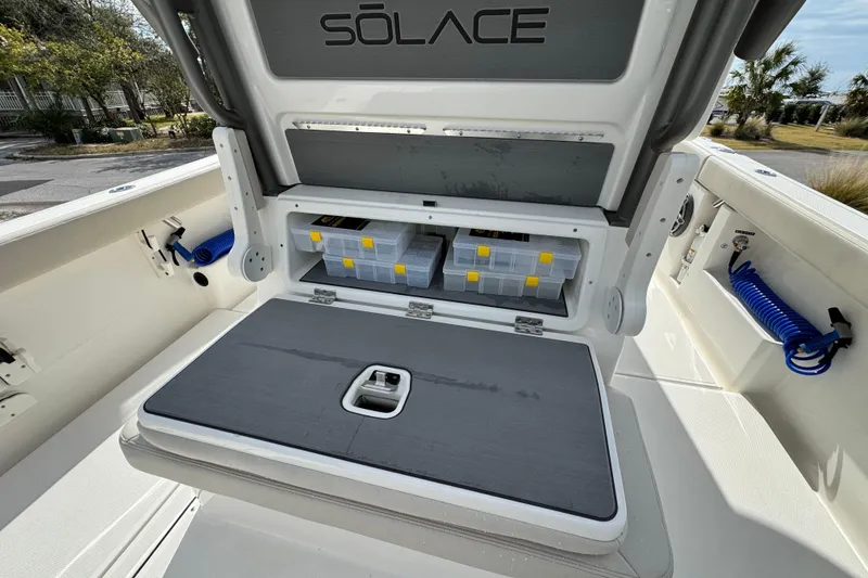 Slide: The Image of 2026 Solace 30 CS boat storage compartment with organized tackle boxes and blue coiled hose. - 15