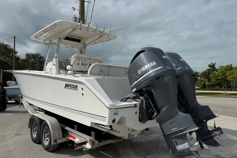 Slide: The Image of 2018 Jupiter 30 boat on trailer, parked outdoors under a partly cloudy sky. - 3