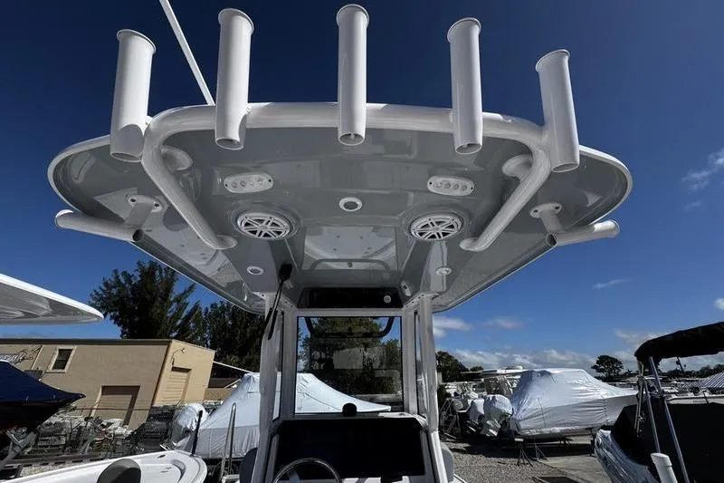 Slide: The Image of 2026 Sportsman Masters 227 Bay Boat with rod holders and speakers under a clear blue sky. - 12