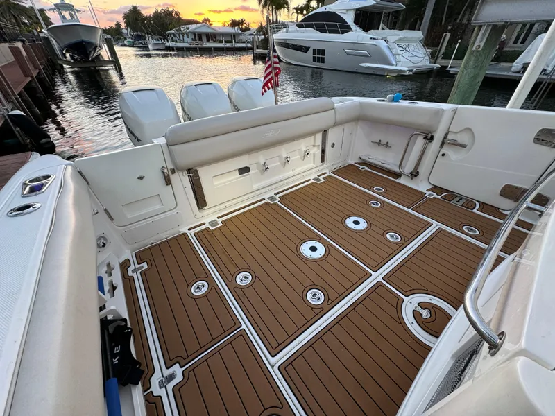 Slide: The Image of 2017 Boston Whaler 370 Outrage boat deck with wooden flooring, docked at sunset. - 10