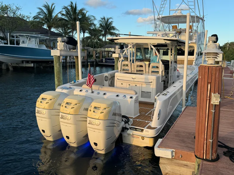 Slide: The Image of 2017 Boston Whaler 370 Outrage docked, featuring triple outboard engines, palm trees in background. - 2