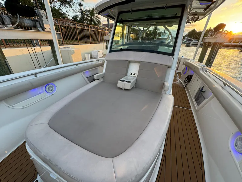 Slide: The Image of 2017 Boston Whaler 370 Outrage boat interior with cushioned seating and sunset view. - 46