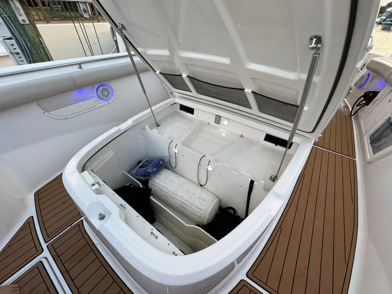 Slide: The Image of Open storage compartment on a 2017 Boston Whaler 370 Outrage boat, featuring teak flooring. - 49