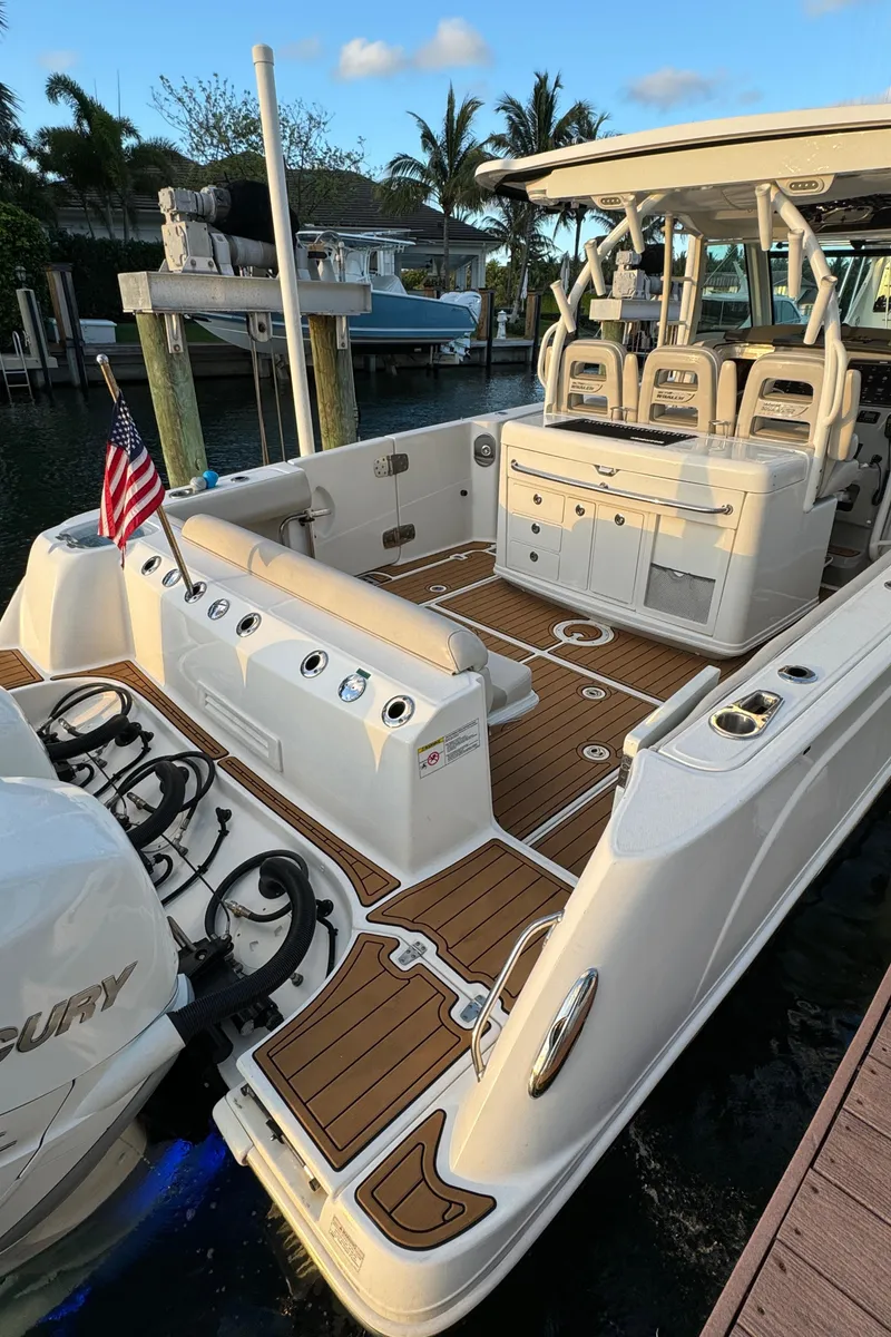 Slide: The Image of 2017 Boston Whaler 370 Outrage boat with spacious deck and seating, docked by palm trees. - 5