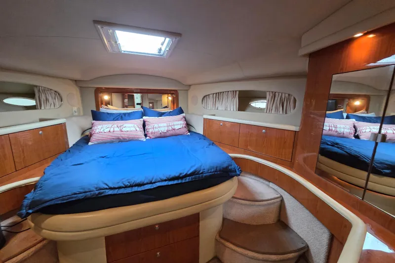 Slide: The Image of Luxurious 2000 Sea Ray 420 Aft Cabin bedroom with blue bedding and wooden cabinetry. - 10