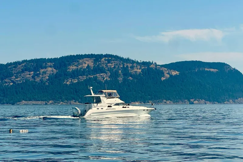 Slide: The Image of Sea Ray 420 Aft Cabin yacht cruising on a serene lake with forested hills. - 29