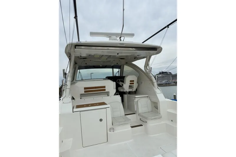 Slide: The Image of 2023 Pursuit OS 355 Offshore boat interior with seating and helm, docked at marina. - 15