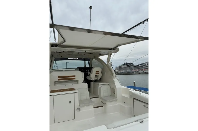 Slide: The Image of 2023 Pursuit OS 355 Offshore boat interior with seating and helm, docked at marina. - 16