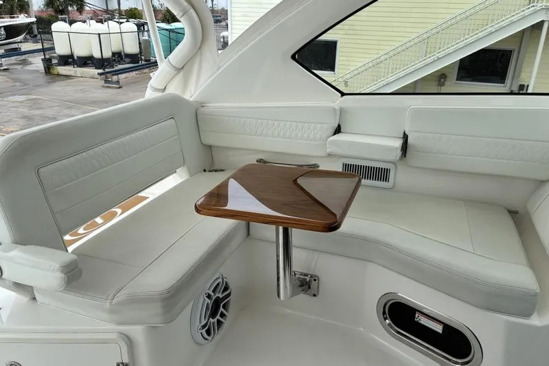 Slide: The Image of 2023 Pursuit OS 355 Offshore boat interior with white seating and wooden table. - 18