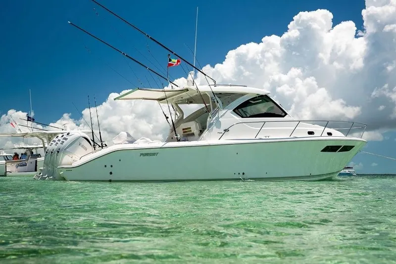 Slide: The Image of 2023 Pursuit OS 355 Offshore boat on dry dock under cloudy sky. - 2