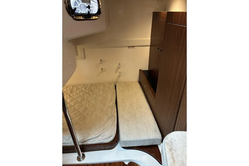 Slide: The Image of 2023 Pursuit OS 355 Offshore cabin interior with twin beds and wooden cabinetry. - 23