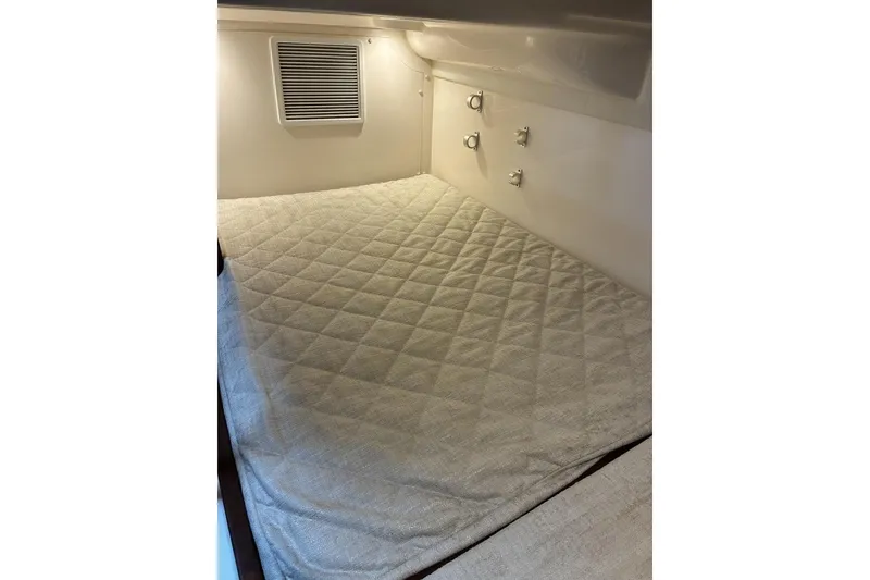 Slide: The Image of 2023 Pursuit OS 355 Offshore cabin interior with quilted bedding and wall fixtures. - 24