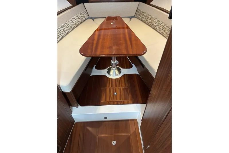 Slide: The Image of 2023 Pursuit OS 355 Offshore cabin interior with wooden table and cushioned seating. - 26