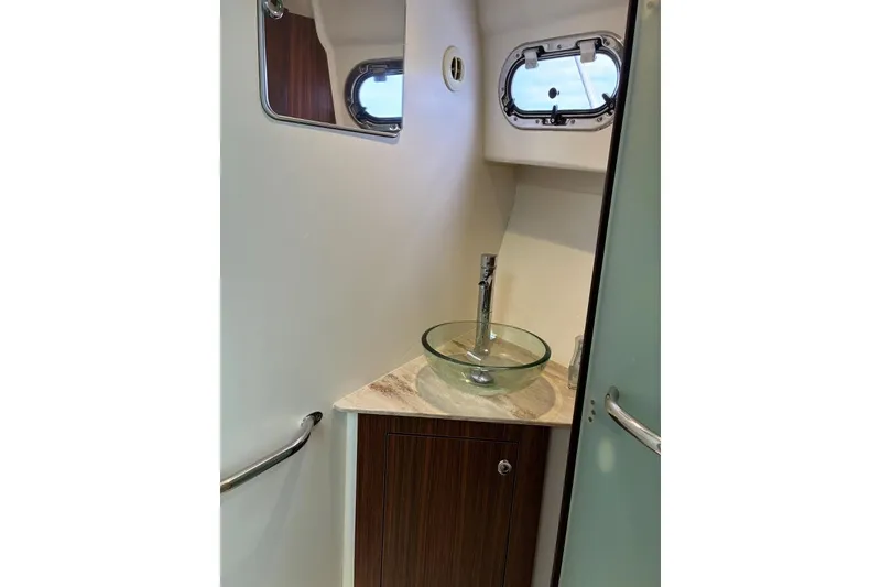 Slide: The Image of 2023 Pursuit OS 355 Offshore boat bathroom with glass sink and porthole window. - 31