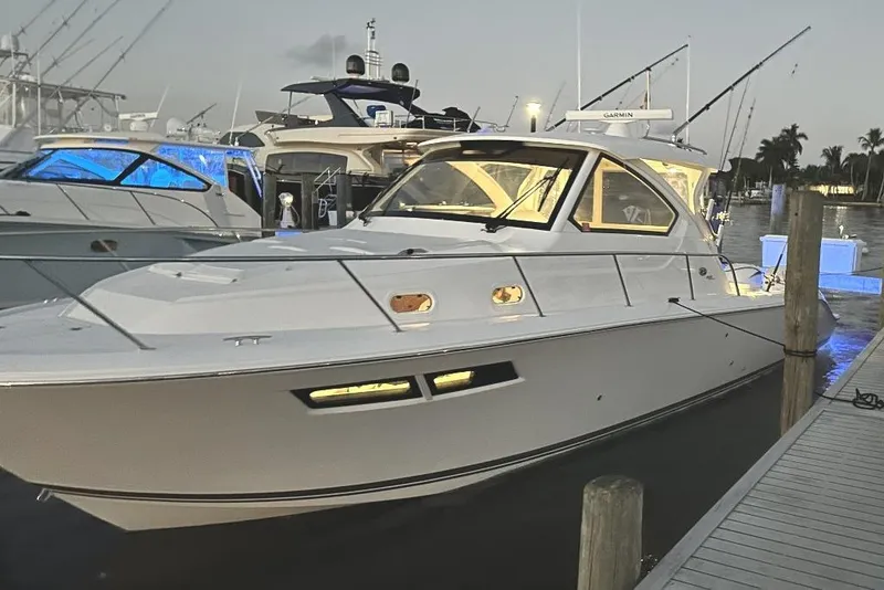 Slide: The Image of 2023 Pursuit OS 355 Offshore boat with triple Yamaha engines docked in a scenic marina. - 5