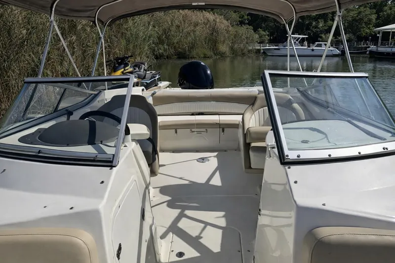 Slide: The Image of 2017 Stingray 234 LR boat interior with seating and canopy on a calm river. - 4