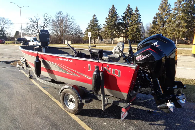 Slide: The Image of 2021 Lund 1775 Pro Guide fishing boat on trailer, parked outdoors. - 2