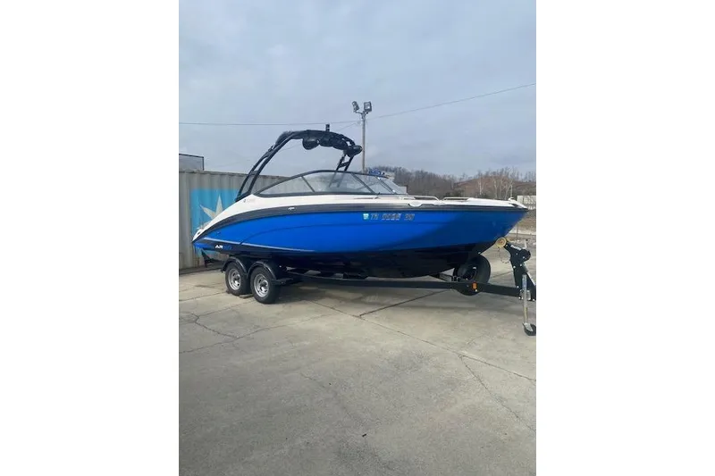 The Image of 2017 Yamaha AR210 boat in blue on a trailer, parked outdoors. - 1