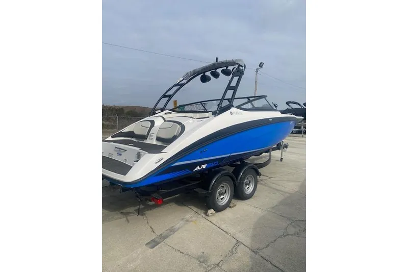 Slide: The Image of 2017 Yamaha AR210 boat on trailer, blue and white design, parked outdoors. - 4