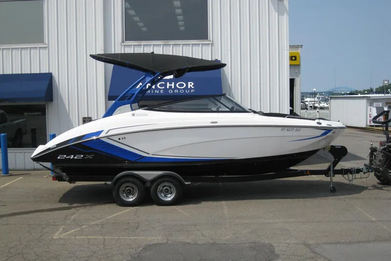 The Image of 2018 Yamaha Boats 242X E-Series on trailer outside marine dealership. - 0