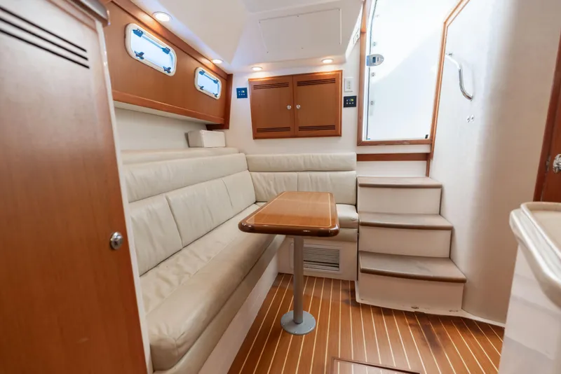 Slide: The Image of Interior of 2000 Cabo 35 Express yacht with wooden flooring and beige seating. - 11