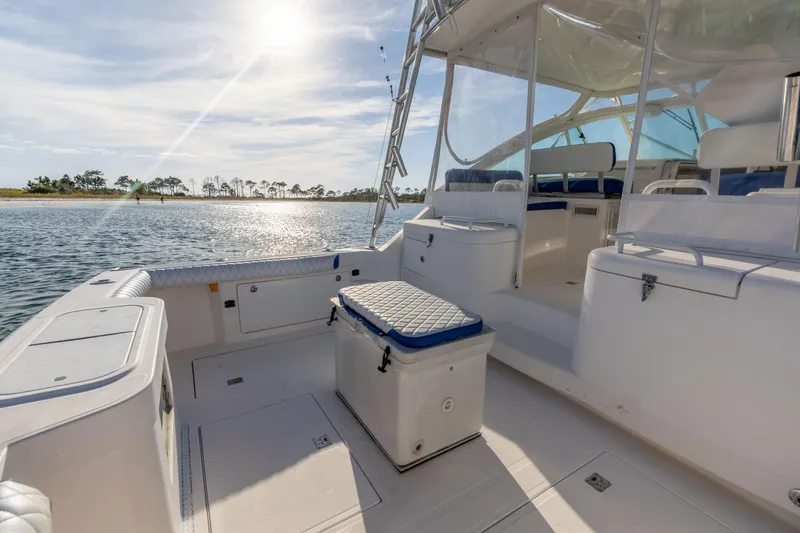 Slide: The Image of 2000 Cabo 35 Express boat interior with seating, cooler, and sunny waterfront view. - 24